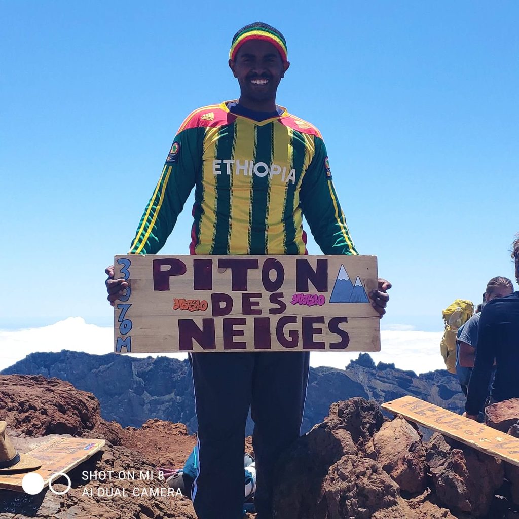 Étudiant éthiopien de l'Université de La Réunion tenant une pancarte avec écrit dessus "Piton des Neiges" 