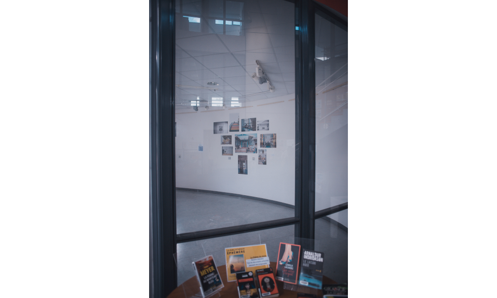 Des photos accrochées à un mur vues à travers une vitre.