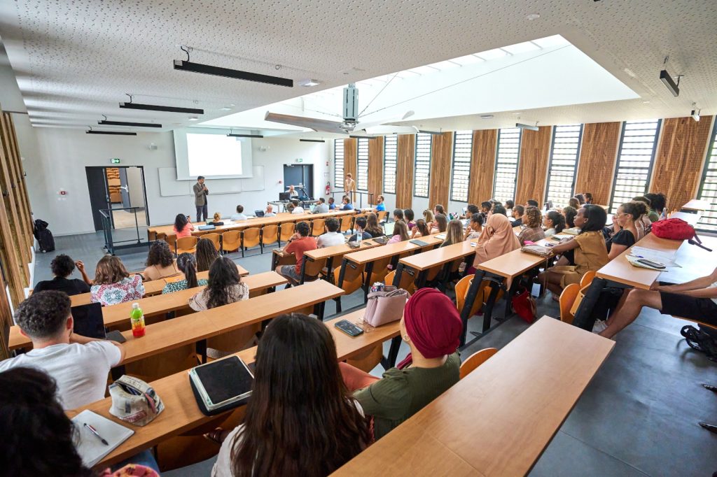 Photo en plan large de la pré-rentrée des étudiants du second cycle de médecine. 
Les étudiants sont de dos, assis, et font face au Président de l'université, Frédéric MIRANVILLE, debout devant un écran pendant sa prise de parole