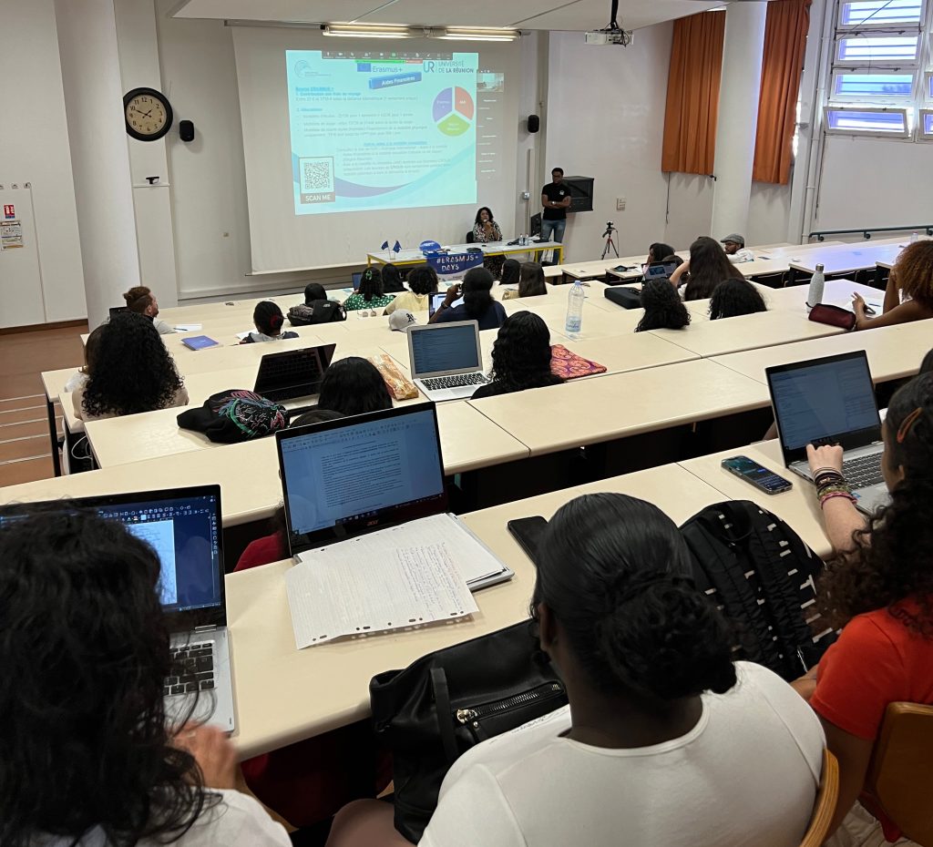 Plan large -
Photo des étudiants de dos, assis en amphithéâtre, pendant une réunion d' information sur les mobilités