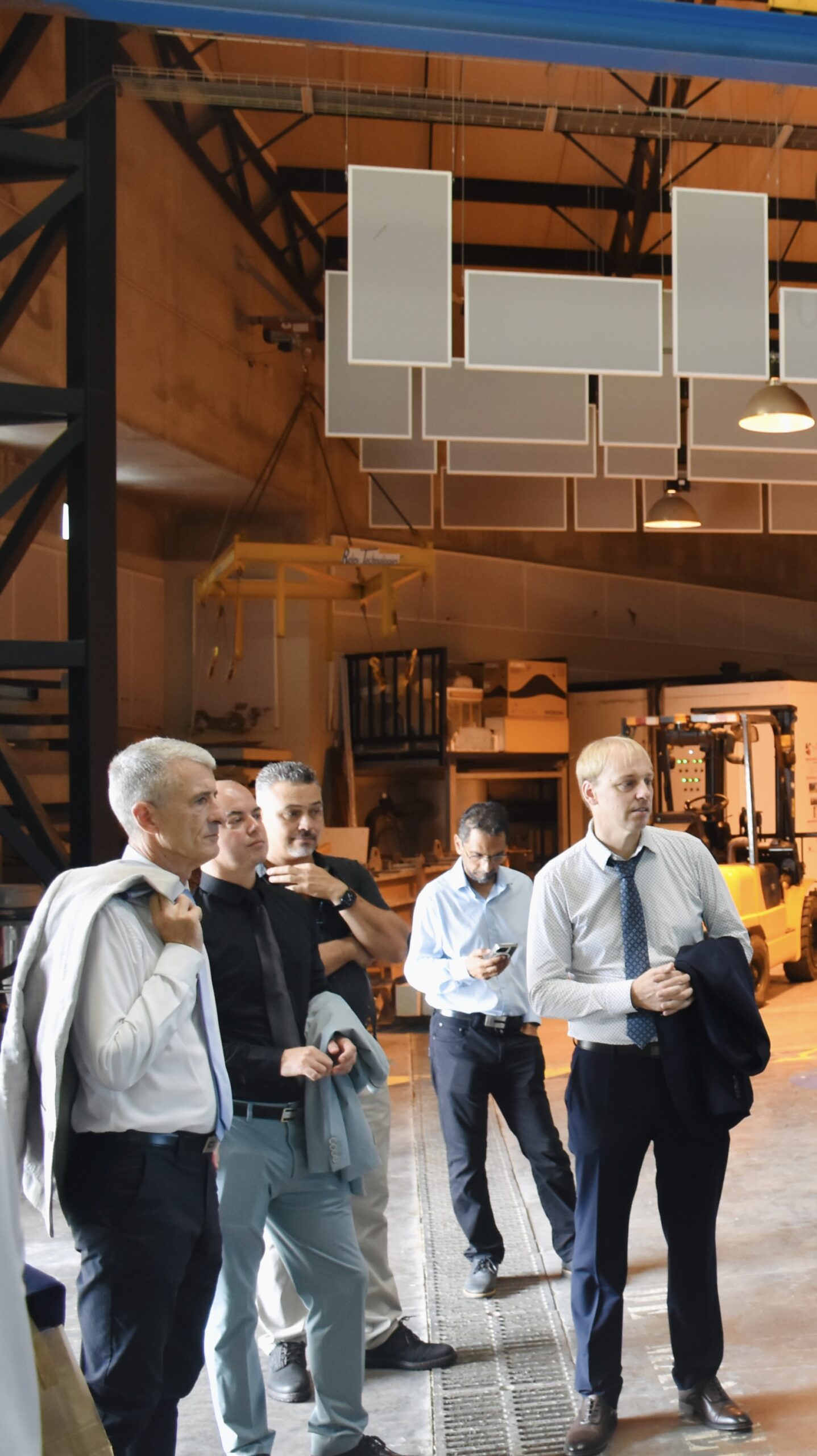 Délégation en tenue professionnelle lors d’une visite d’un site industriel, dans un atelier équipé de machines et de structures techniques.