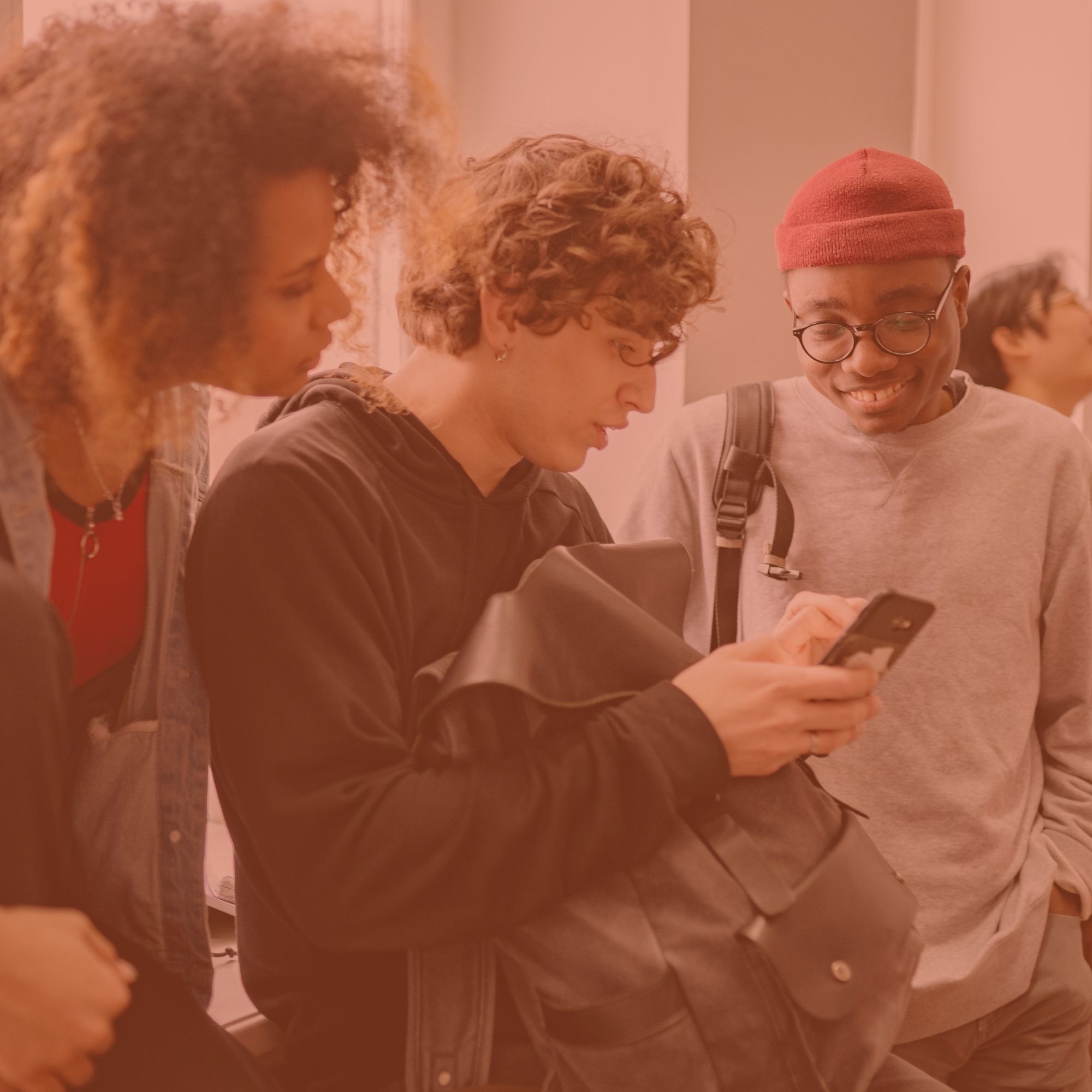 Un groupe d'étudiants qui discutent, l'un d'eux regardant son téléphone.