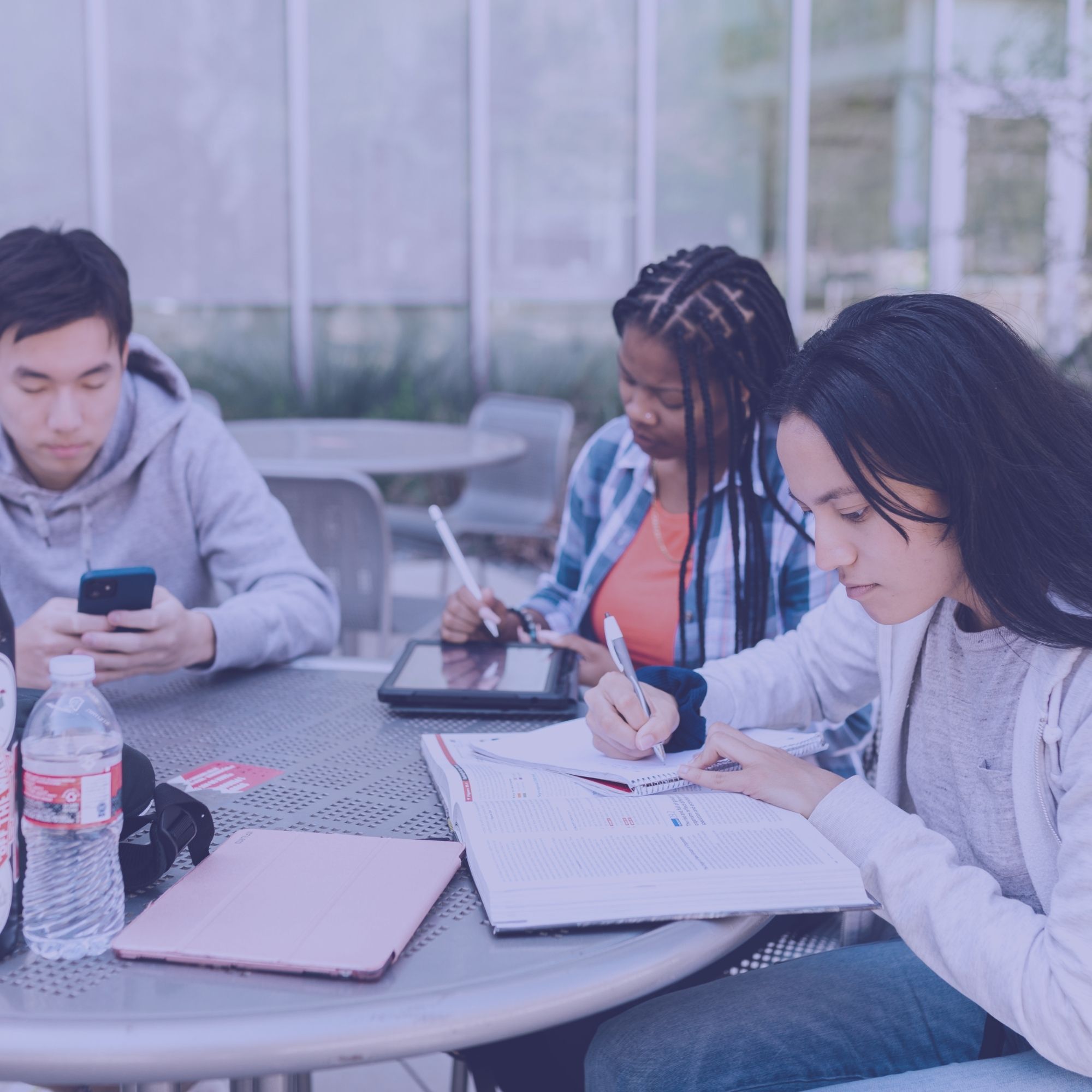 Trois étudiants qui révisent autour d'une table en extérieur