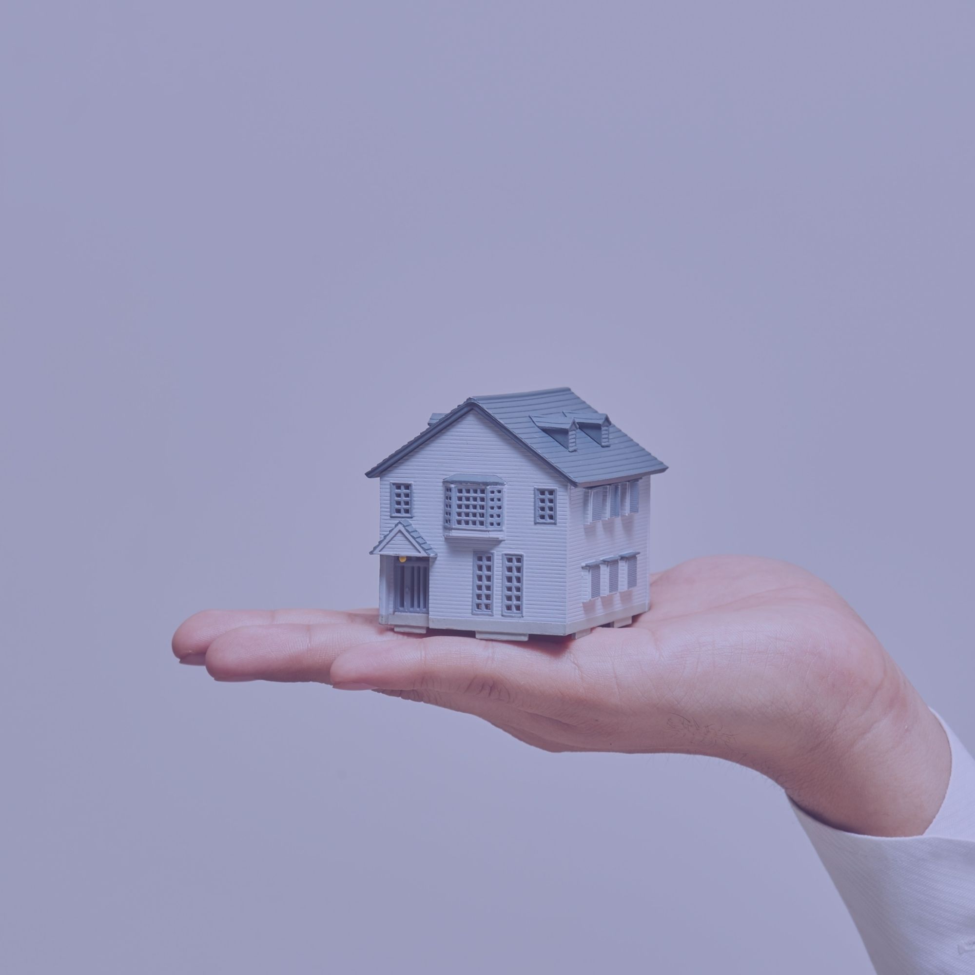 Une main tenant une maquette de maison.