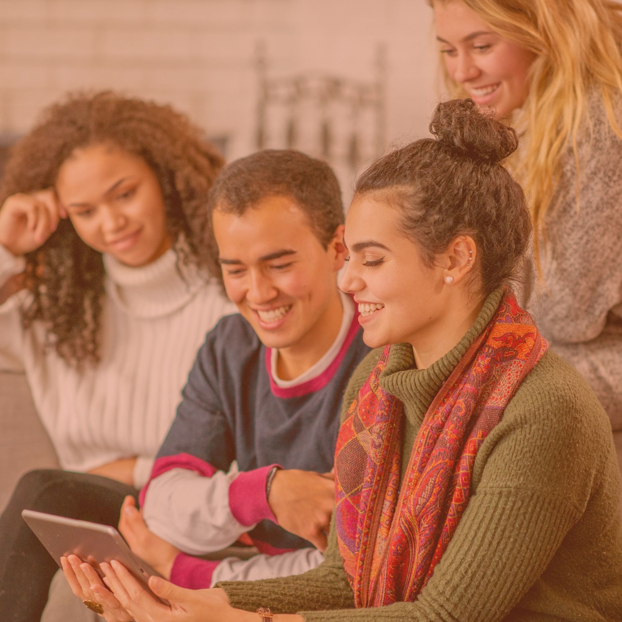 Quatre étudiants souriants, rassemblés autour d'une tablette.